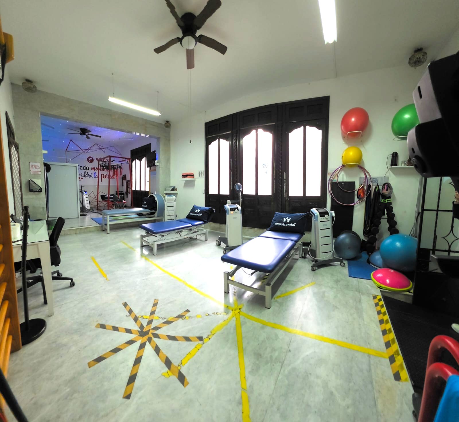 Interior de la clínica ImpulsandoT: camillas con la marca, equipo de alta tecnología y área de Redcord al fondo